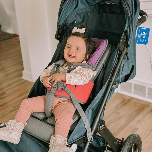 Young girl smiling indoors seated in a WeGo pushchair