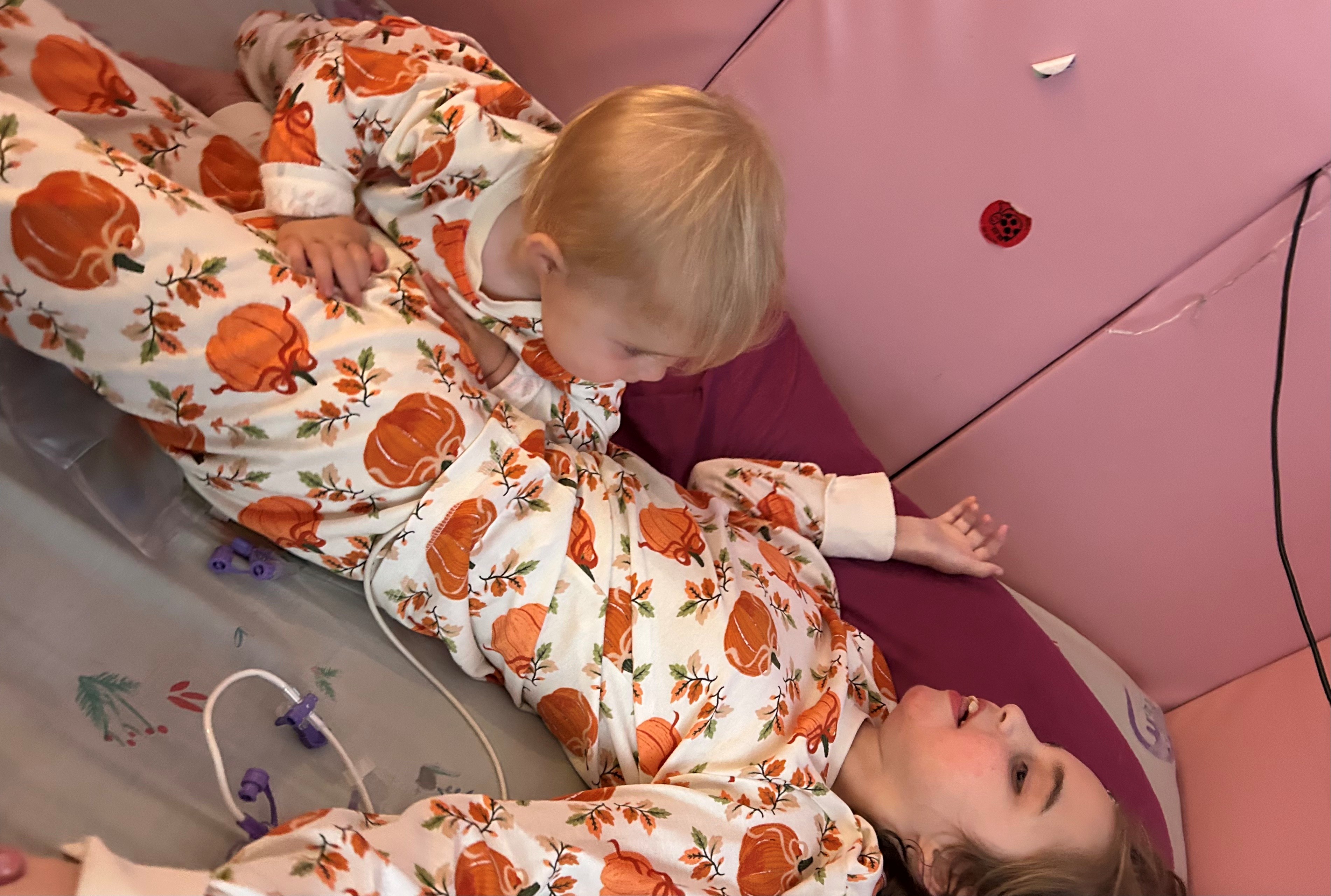 2 sisters next to each other in matching pumpkin pyjamas