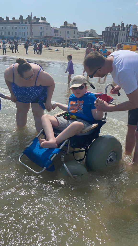 Parents at the beach with their son in an accessible beach wheelchair