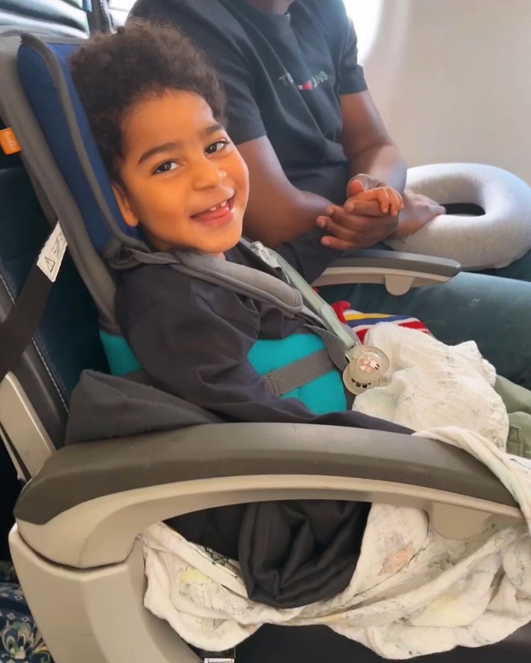 A child sits in a postural support seat on a plane