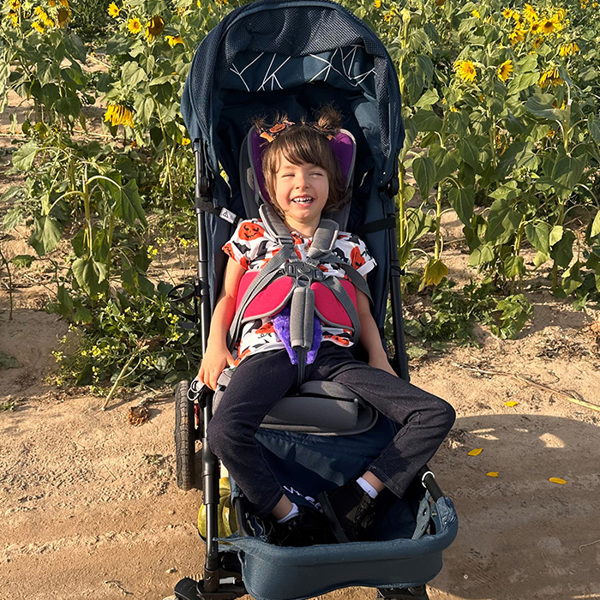 Young girl smiling outdoors in a sunflower field in a WeGo pushchair