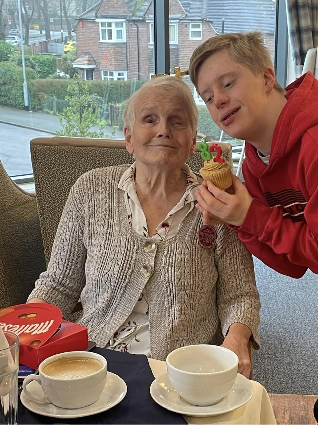 A woman and her grandson smile at the camera together.