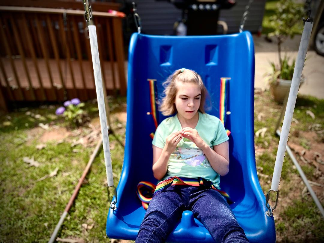 A little girl sitting in an accessible swing