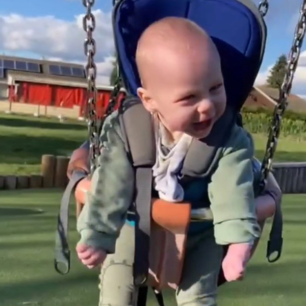 Toddler boy laughing and having fun outdoors on a swing, supported by the GoTo Seat