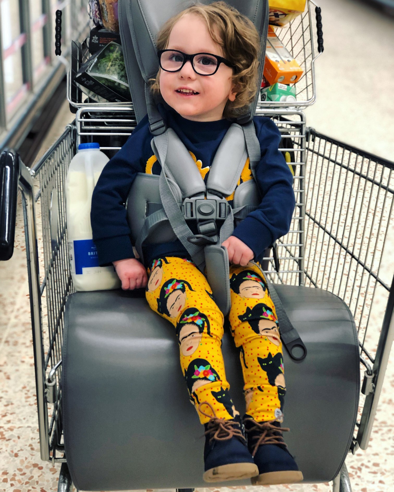 Un niño se sienta felizmente apoyado en un carrito de la compra accesible, el GoTo Shop