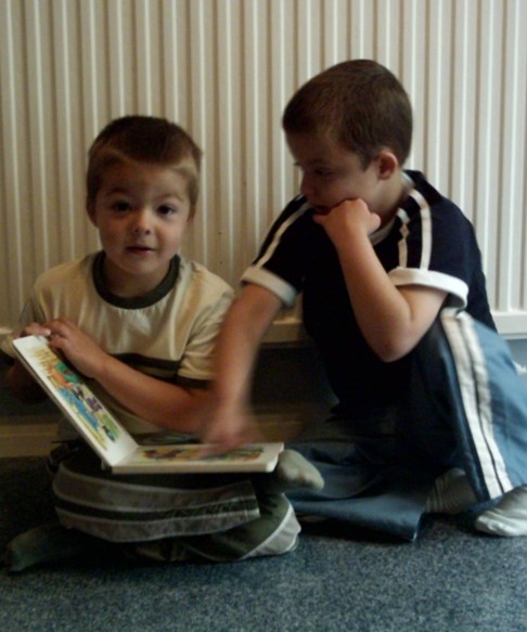 Two brothers sit together with a book.