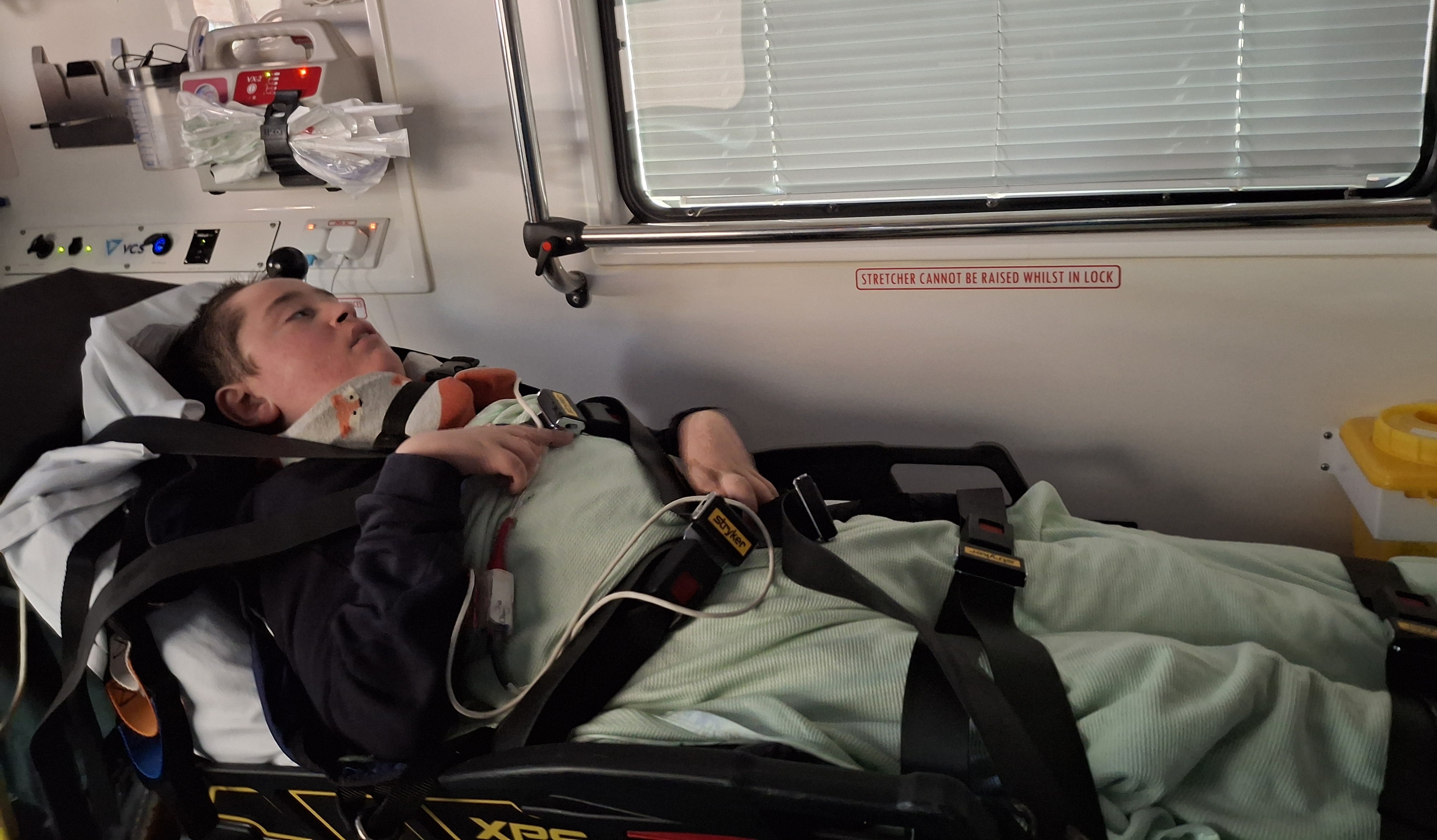 A young man lays in an ambulance