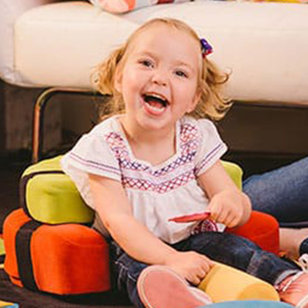 A little girl smiles in her Playpak