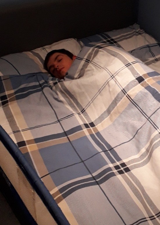 Young boy sleeping in a bed with checked bedding