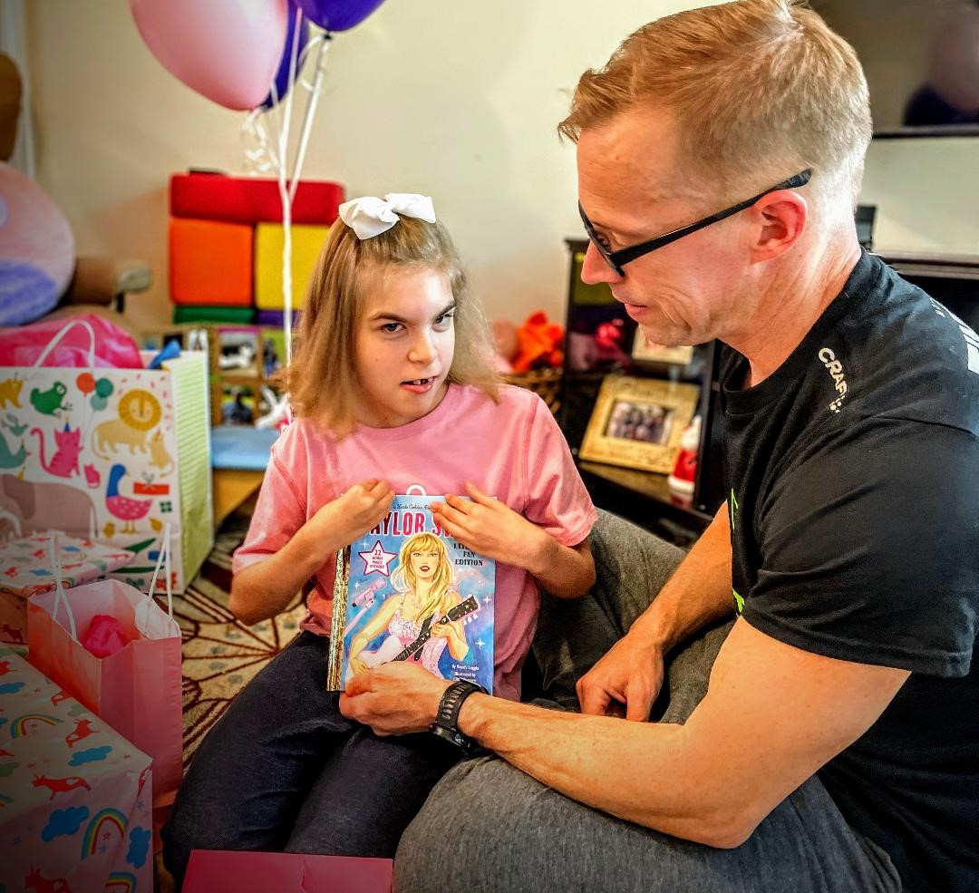 A young girl opens gifts with her family.