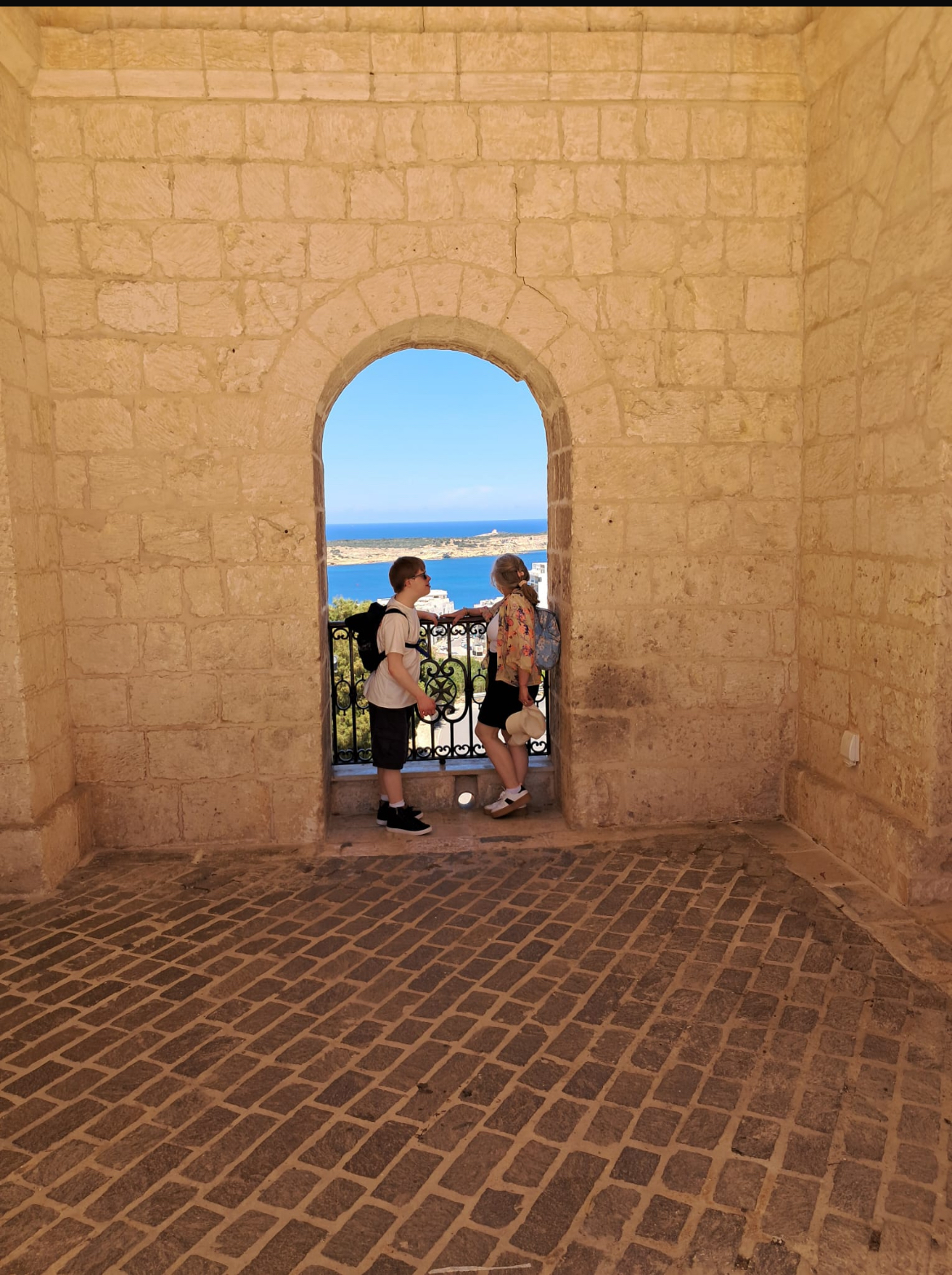 A mother and son gaze out a sea view window on holiday