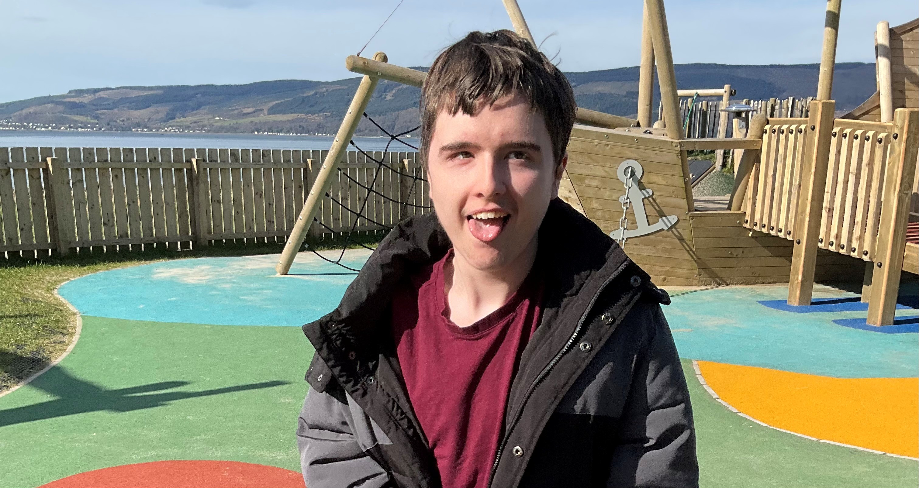 A happy young man looks at the camera while at a park