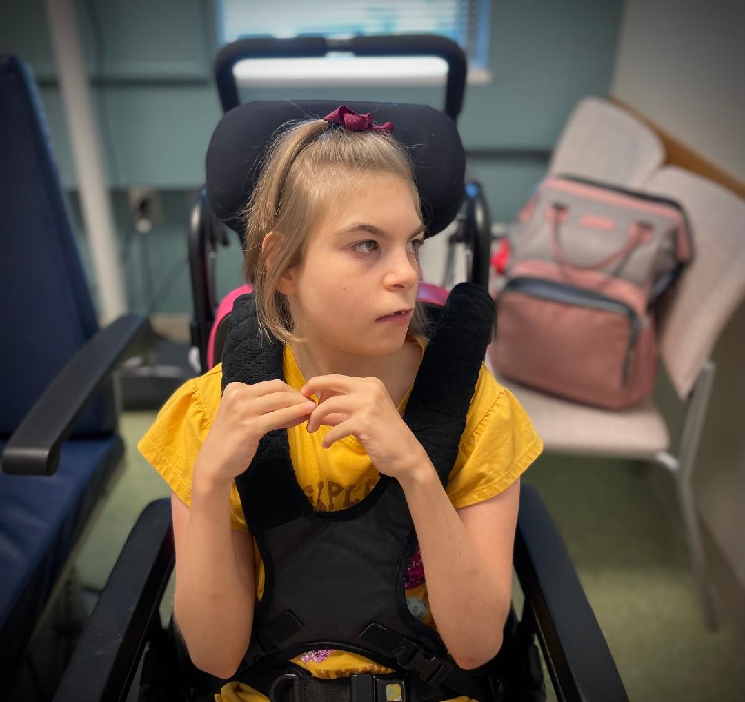 A young girl sits in an adaptive seat