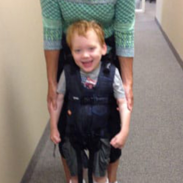 A little girl smile sin her supportive Upsee mobility harness