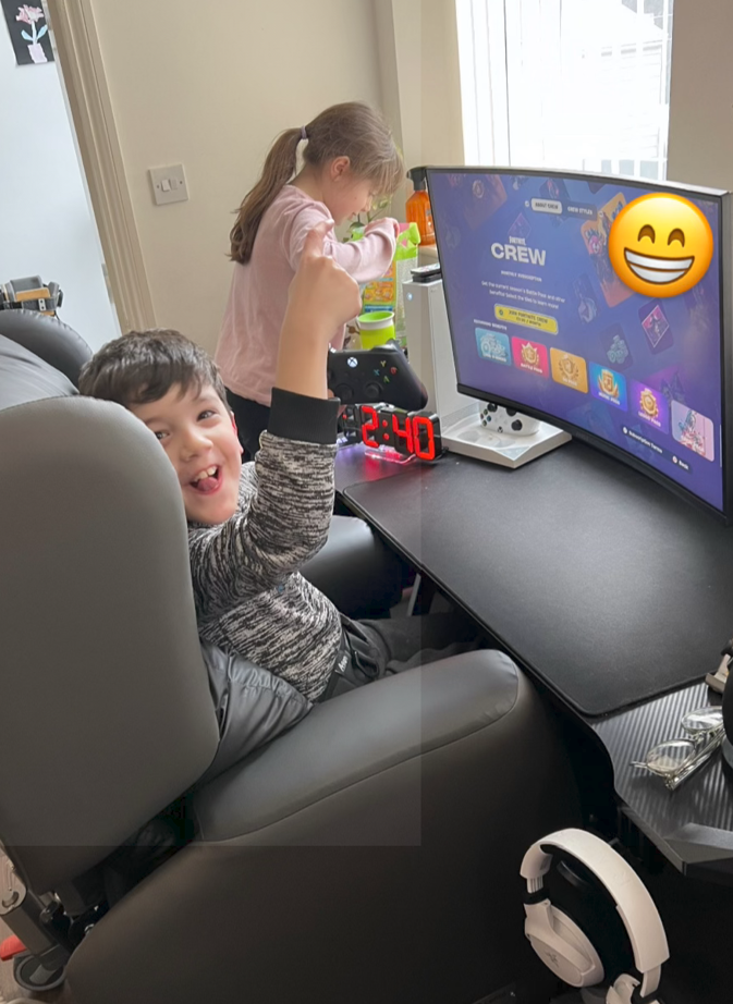 A young boy smiles as he sits at his video gaming station